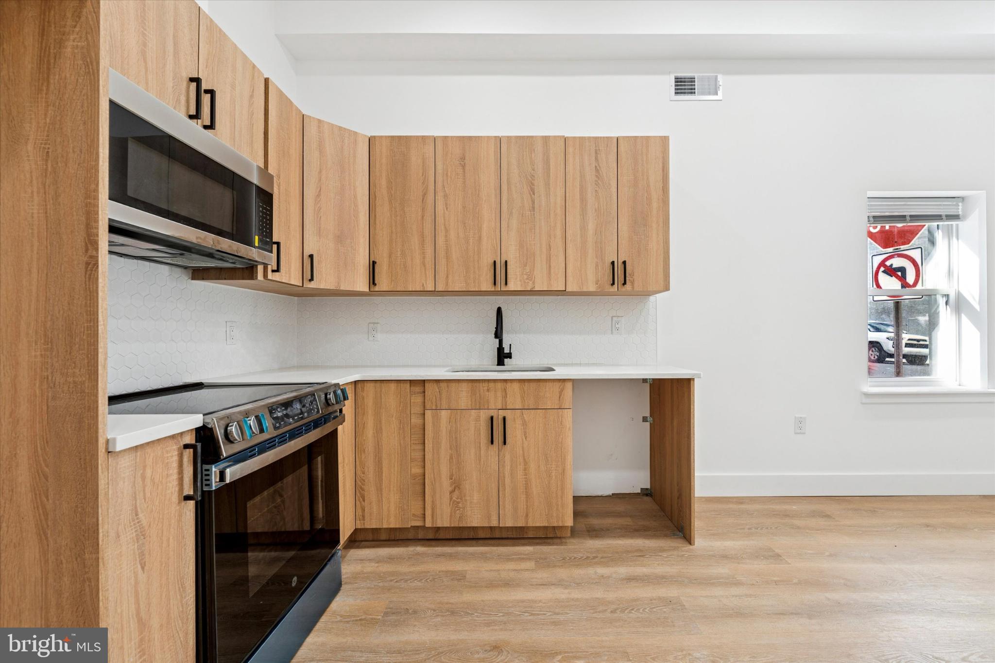 2424 West Thompson Street, Unit 3 Philadelphia, PA 19121 - Photo 5 of 14 a kitchen with stainless steel appliances granite countertop a stove a microwave and a refrigerator