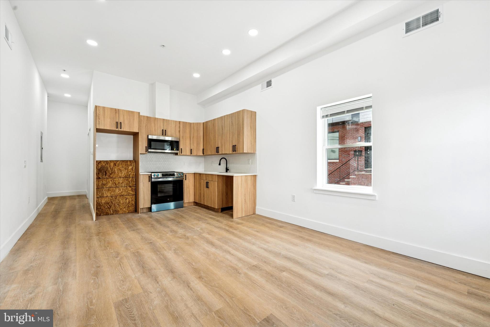 2424 West Thompson Street, Unit 3 Philadelphia, PA 19121 - Photo 7 of 14 a view of kitchen with stainless steel appliances granite countertop a stove top oven a sink dishwasher and a refrigerator with wooden floor