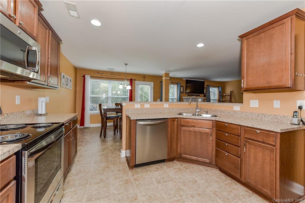 10818 Greenhead View Road Charlotte, NC 28262 - Photo 13 of 39 a kitchen with stainless steel appliances granite countertop a stove top oven a sink dishwasher a dining table and chairs with wooden floor
