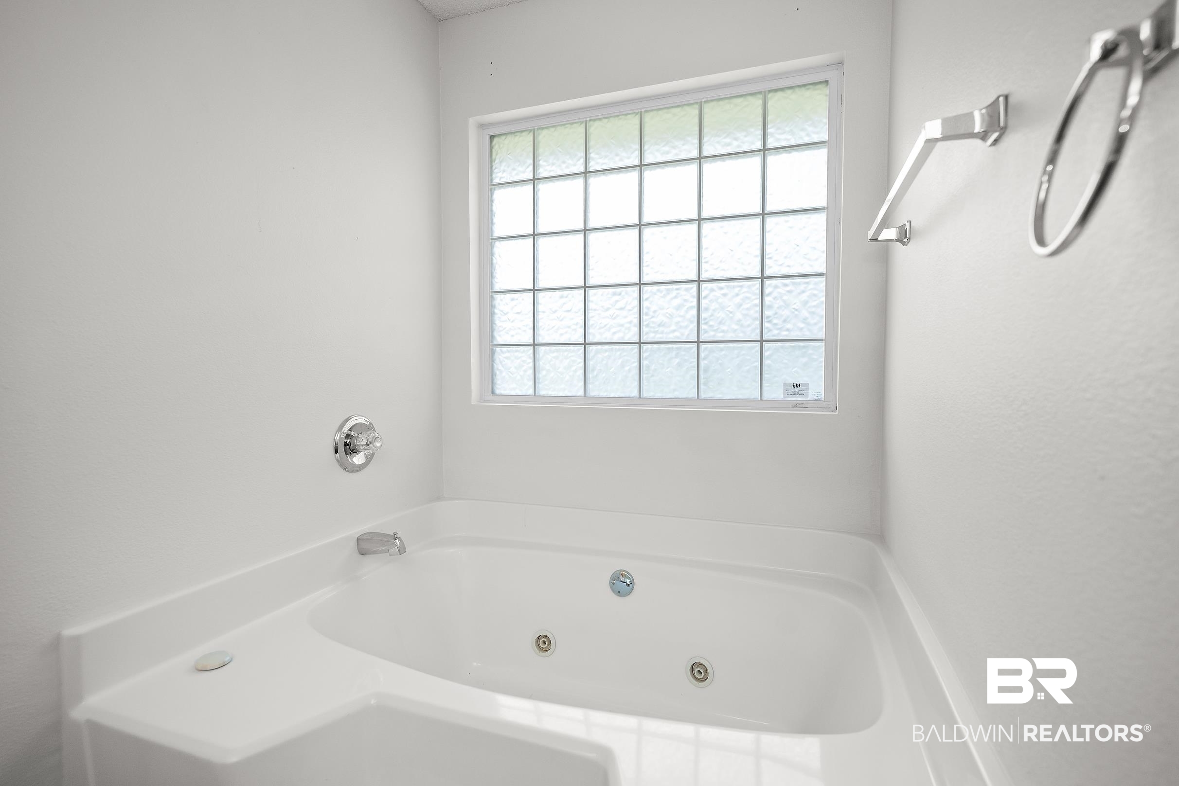 323 Manchester Lane Foley, AL 36535 - Photo 15 of 30 White jetted soaking tub with chrome fixtures and a frosted privacy window