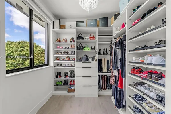 a view of walk in closet with clothes and shoes
