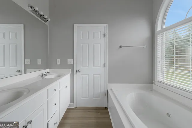 a spacious bathroom with a tub sink and mirror