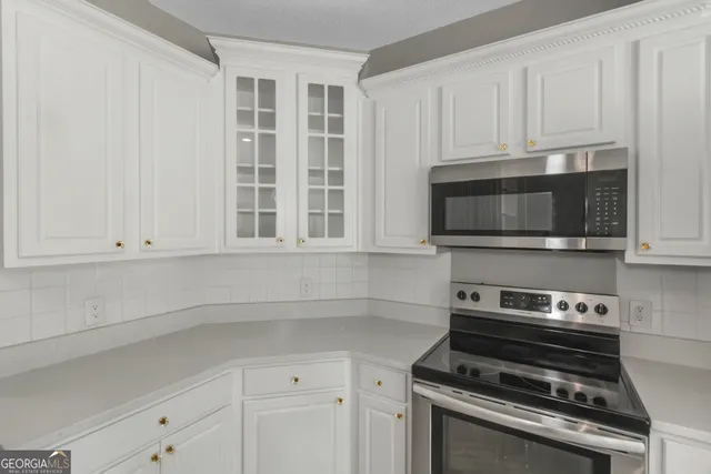 a kitchen with stainless steel appliances a stove a microwave and white cabinets