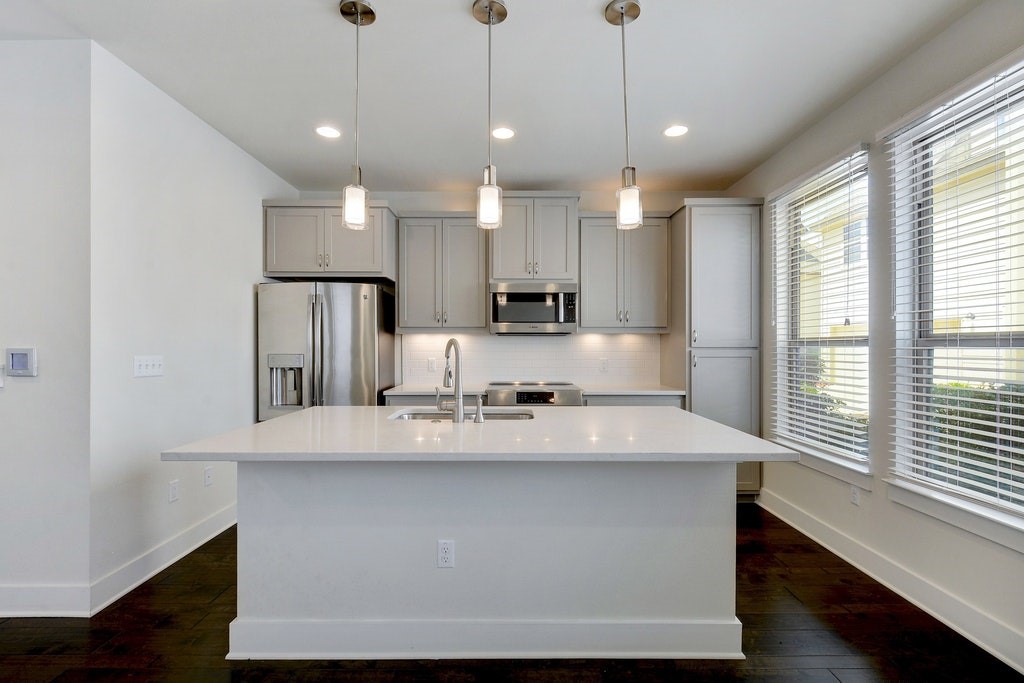a large kitchen with kitchen island a large counter space a sink appliances and a window