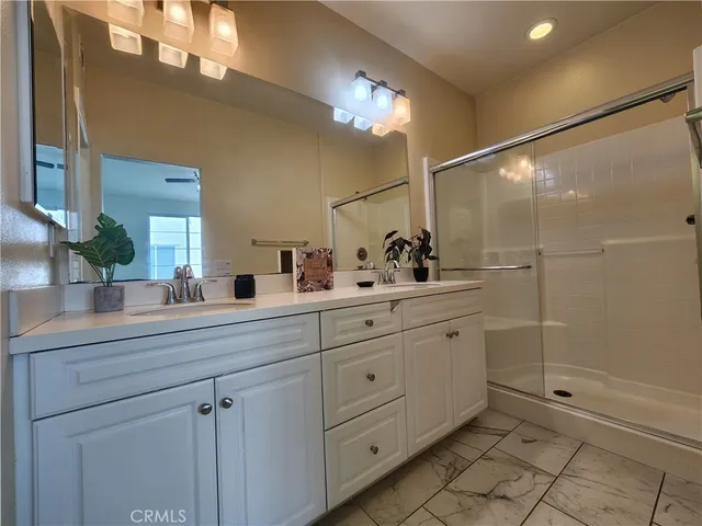 a bathroom with a double vanity sink mirror and shower