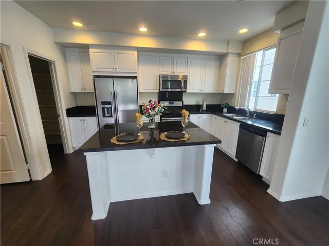 a kitchen with kitchen island wooden floors appliances and cabinets