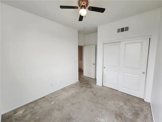 an empty room with a ceiling fan and closet area