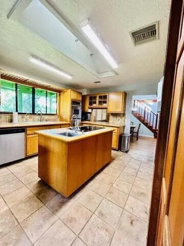 a large kitchen with stainless steel appliances granite countertop a large counter top a stove a sink and a refrigerator
