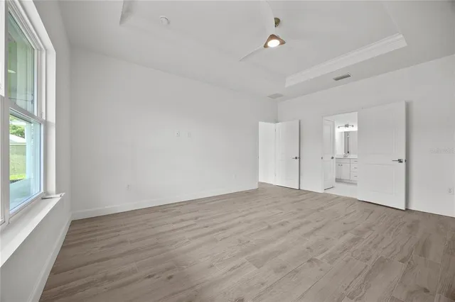 an empty room with wooden floor ceiling fan and windows
