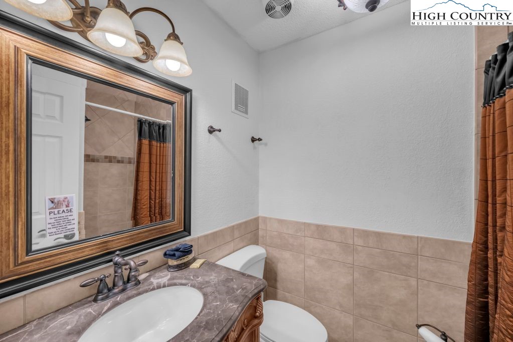 301 Pinnacle Inn Road, Unit 4314 Beech Mountain, NC 28604 - Photo 18 of 39 a bathroom with a granite countertop sink a toilet and a mirror