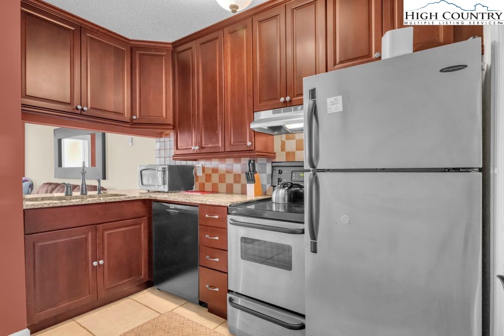 301 Pinnacle Inn Road, Unit 4314 Beech Mountain, NC 28604 - Photo 9 of 39 a kitchen with stainless steel appliances granite countertop a refrigerator sink and cabinets