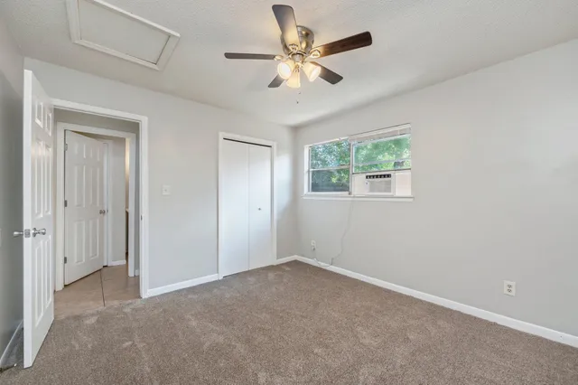 an empty room with windows and fan
