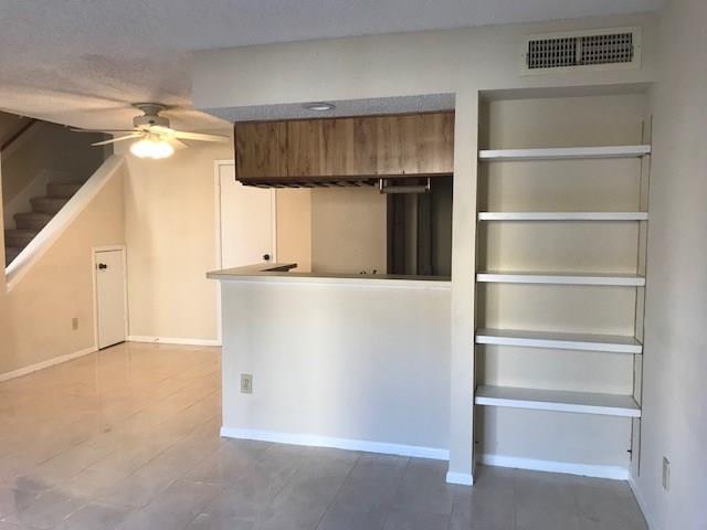 This unit is one of the larger one-bedroom units. It is 888 sq. ft. Notice the passthrough from the kitchen to the  living area. New ceiling fan with light in breakfast area.  Extra storage is under the stairs. Tile floor is whiter then shown in photo.