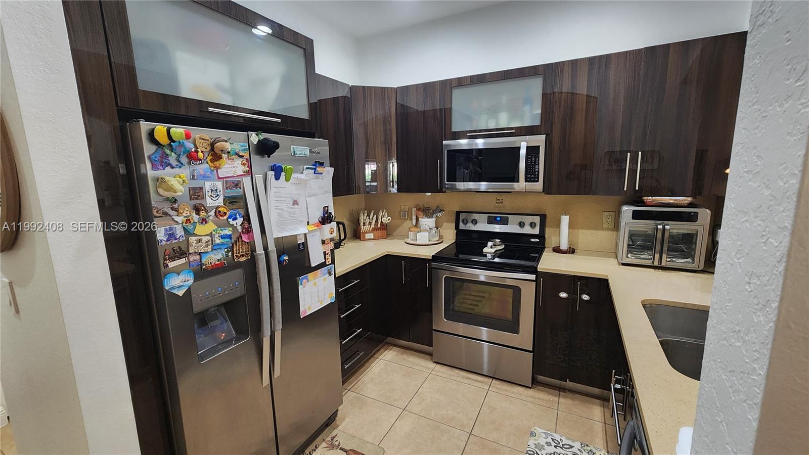 2607 Southwest 99th Way Miramar, FL 33025 - Photo 14 of 50 a kitchen with stainless steel appliances granite countertop a refrigerator stove and microwave