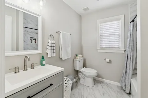 a bathroom with a sink toilet vanity and window