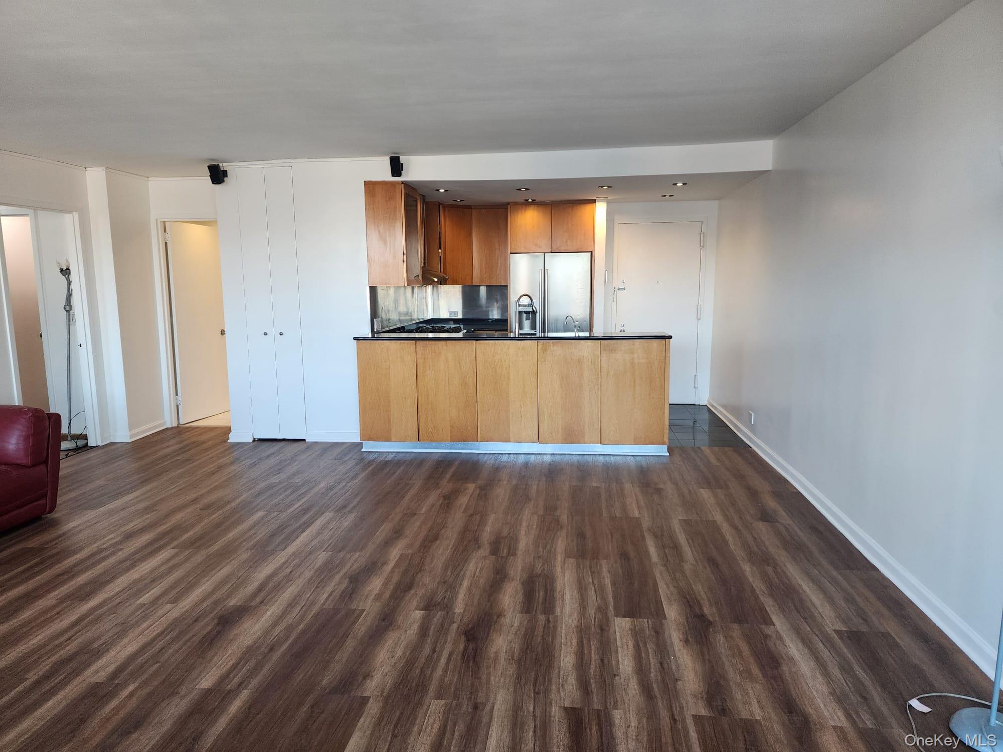 62-54 97th Place, Unit 12J Queens, NY 11374 - Photo 12 of 12 Kitchen featuring open floor plan, brown cabinetry, dark countertops, and a peninsula