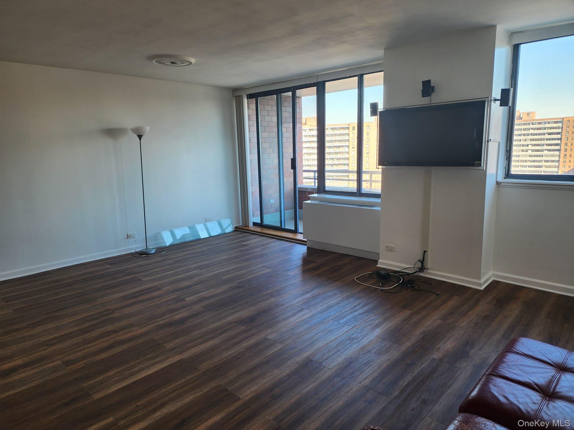62-54 97th Place, Unit 12J Queens, NY 11374 - Photo 4 of 12 Unfurnished living room with dark wood-style flooring and baseboards