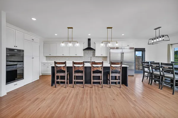 a kitchen with stainless steel appliances granite countertop a stove a sink a microwave dining table and chairs