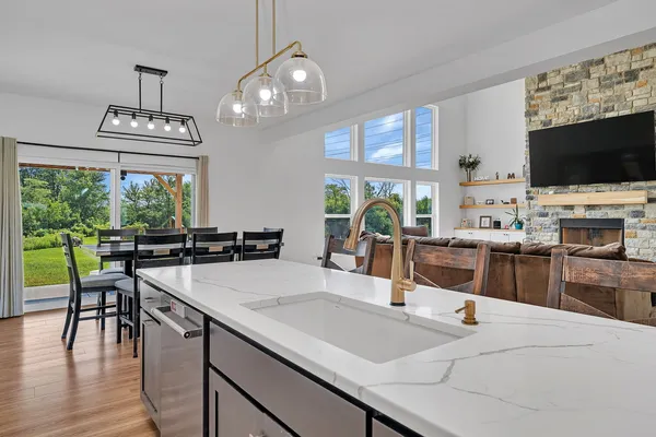 a kitchen with stainless steel appliances granite countertop a stove a sink and white cabinets with wooden floor