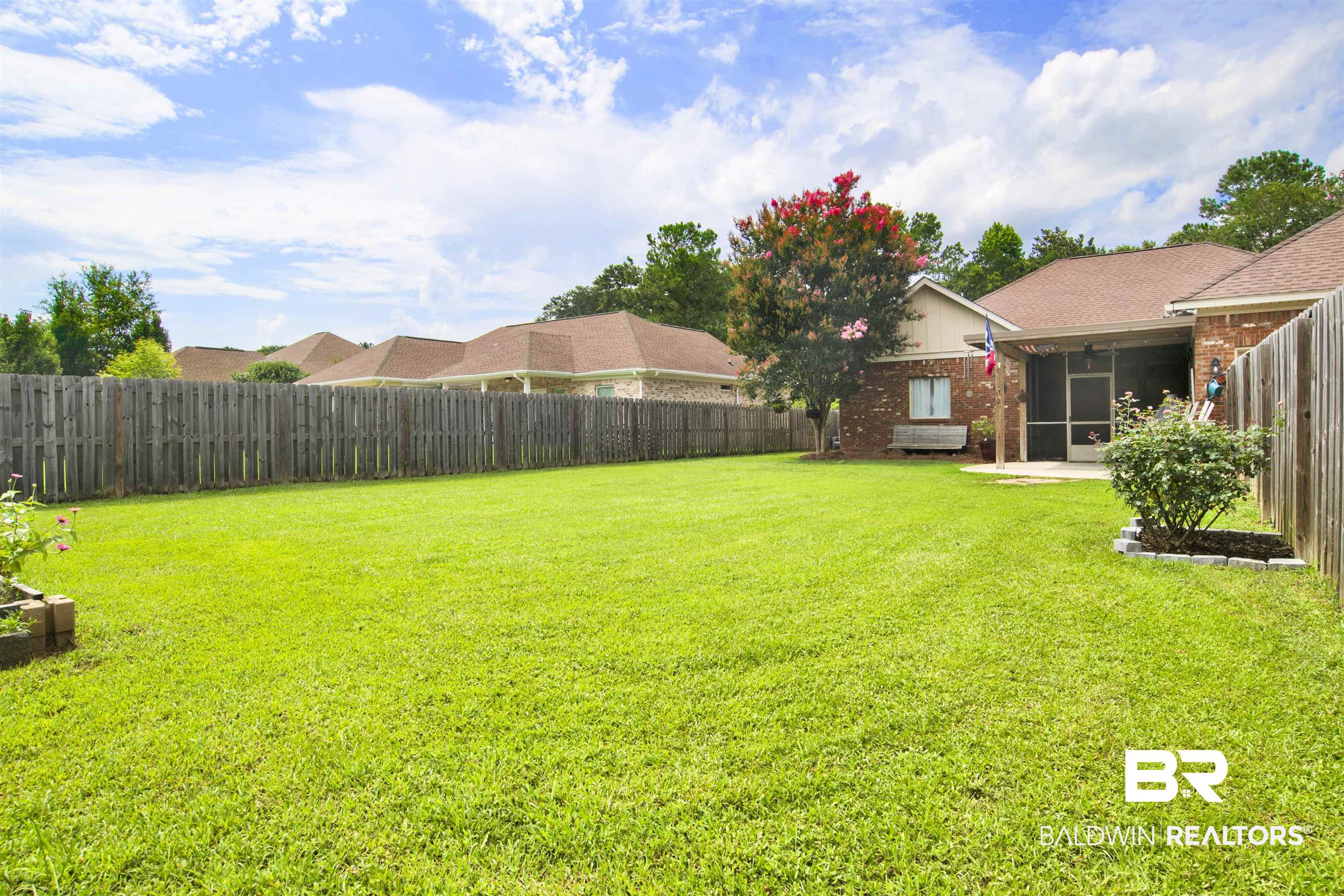 10368 Gayfer Rd Extension Fairhope, AL 36532 - Photo 39 of 43 Expansive backyard featuring a lush lawn, privacy fencing, a flowering tree, and a screened patio