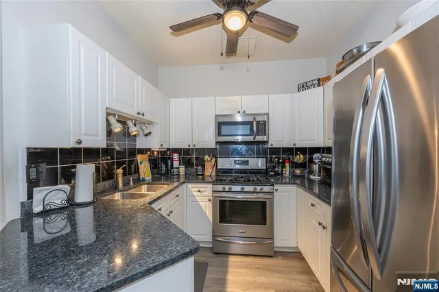 a kitchen with stainless steel appliances granite countertop a sink a stove and a refrigerator