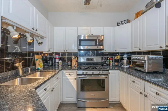 a kitchen with stainless steel appliances granite countertop a sink a stove and a microwave