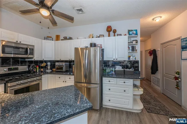 a kitchen with stainless steel appliances kitchen island granite countertop a refrigerator and a stove top oven