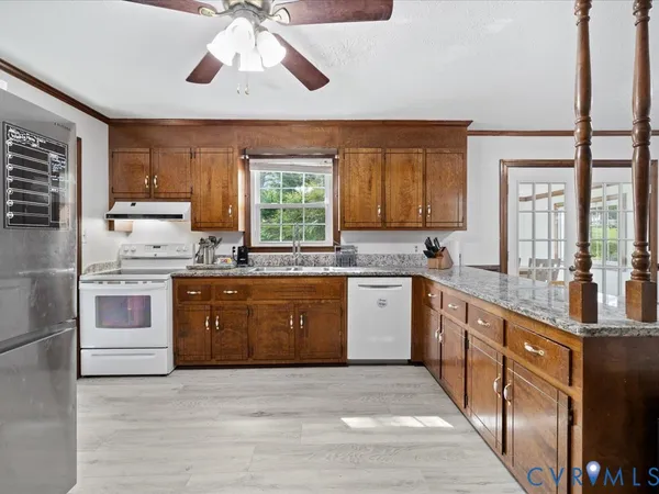 a kitchen with stainless steel appliances granite countertop wooden cabinets a stove a sink and a large window
