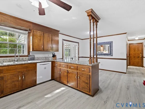 a living room with stainless steel appliances furniture a kitchen view and a large window