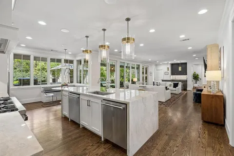 a large kitchen with kitchen island a large window a sink and stainless steel appliances