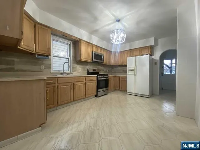 a kitchen with stainless steel appliances a refrigerator a stove a sink cabinets and a dining table