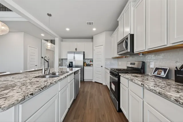 a large kitchen with stainless steel appliances granite countertop a lot of counter space a sink and dishwasher a stove top oven with wooden floor