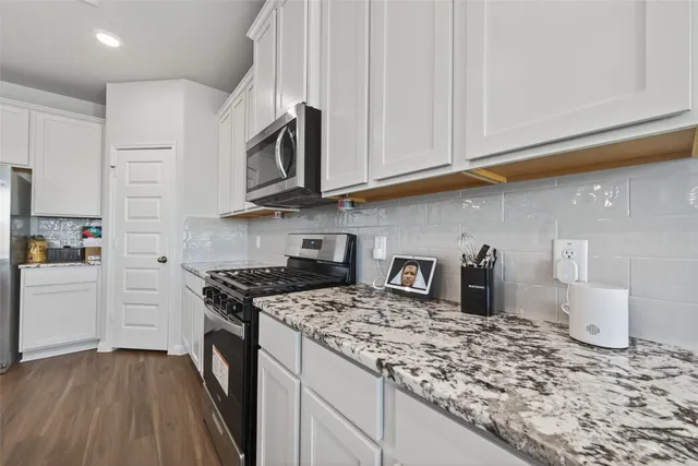a kitchen with stainless steel appliances granite countertop a stove a sink and a microwave