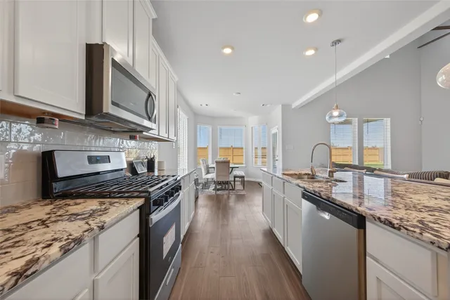 a kitchen with stainless steel appliances granite countertop a lot of counter space a sink and a stove