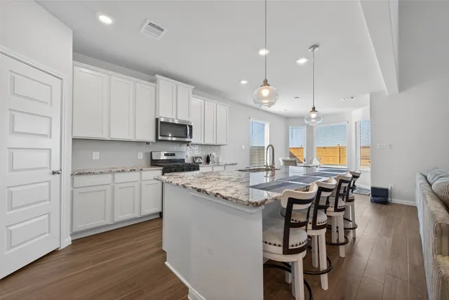 a kitchen with stainless steel appliances granite countertop a table chairs sink and cabinets