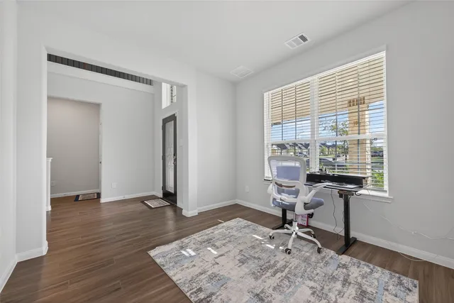 a view of a workspace with wooden floor and a window