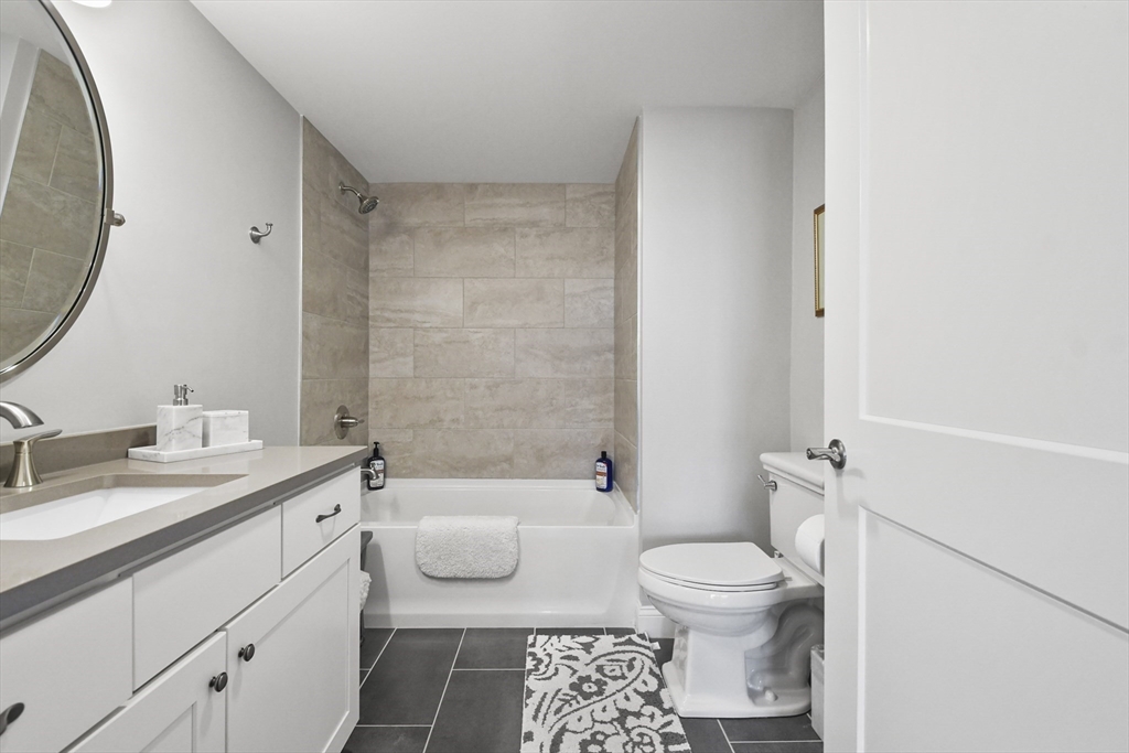 635 Old Post Road, Unit 108 Sharon, MA 02067 - Photo 14 of 42 a bathroom with a granite countertop toilet a sink and a mirror