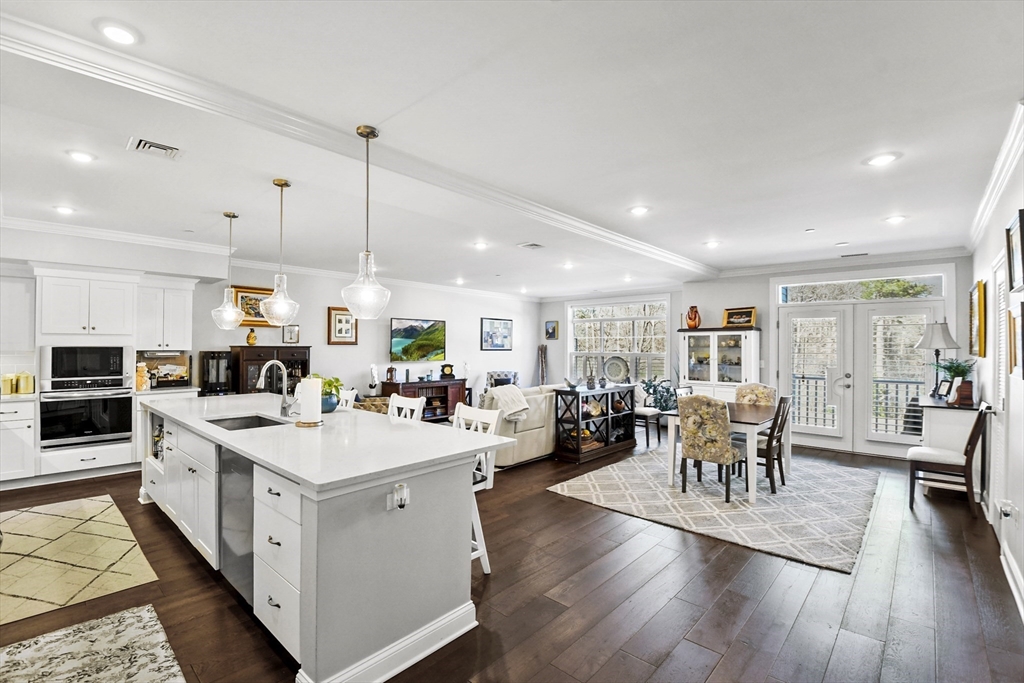 635 Old Post Road, Unit 108 Sharon, MA 02067 - Photo 2 of 42 a large white dining hall with stainless steel appliances granite countertop a stove oven a dining table chairs with wooden floor