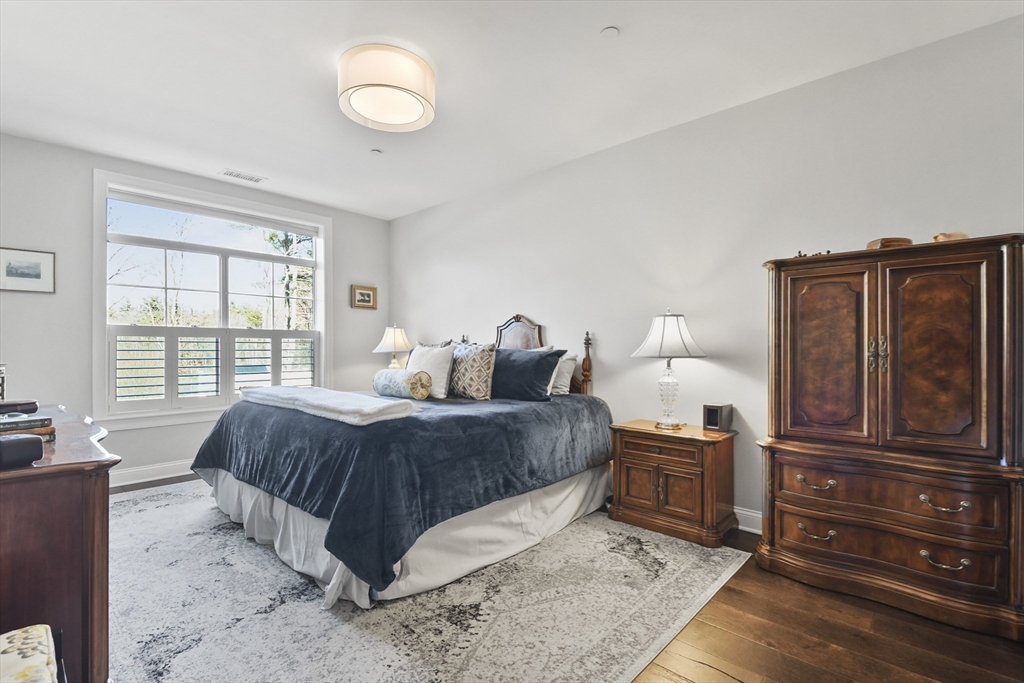 635 Old Post Road, Unit 108 Sharon, MA 02067 - Photo 23 of 42 a spacious bedroom with a bed and wooden floor