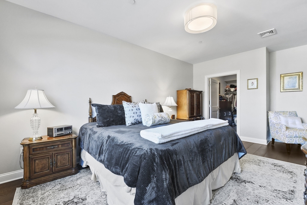 635 Old Post Road, Unit 108 Sharon, MA 02067 - Photo 24 of 42 a bedroom with a bed and wooden floor