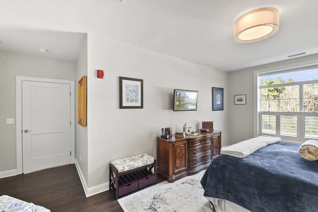 635 Old Post Road, Unit 108 Sharon, MA 02067 - Photo 27 of 42 a bedroom with a bed and wooden floor