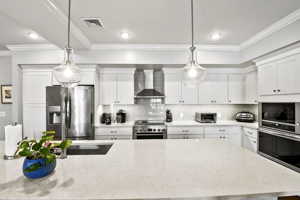 635 Old Post Road, Unit 108 Sharon, MA 02067 - Photo 4 of 42 a kitchen with stainless steel appliances kitchen island granite countertop a refrigerator a stove a sink and white cabinets