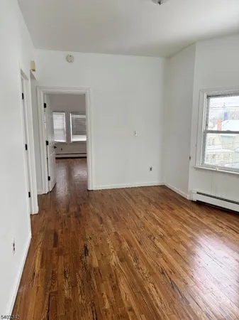 a view of empty room with wooden floor and window