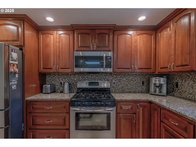 a kitchen with granite countertop stainless steel appliances a stove a sink and a microwave