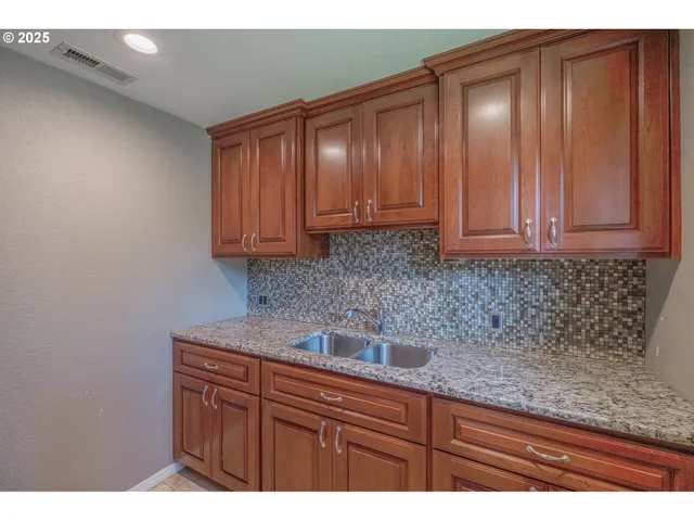 a kitchen with granite countertop wood cabinets stainless steel appliances and a sink
