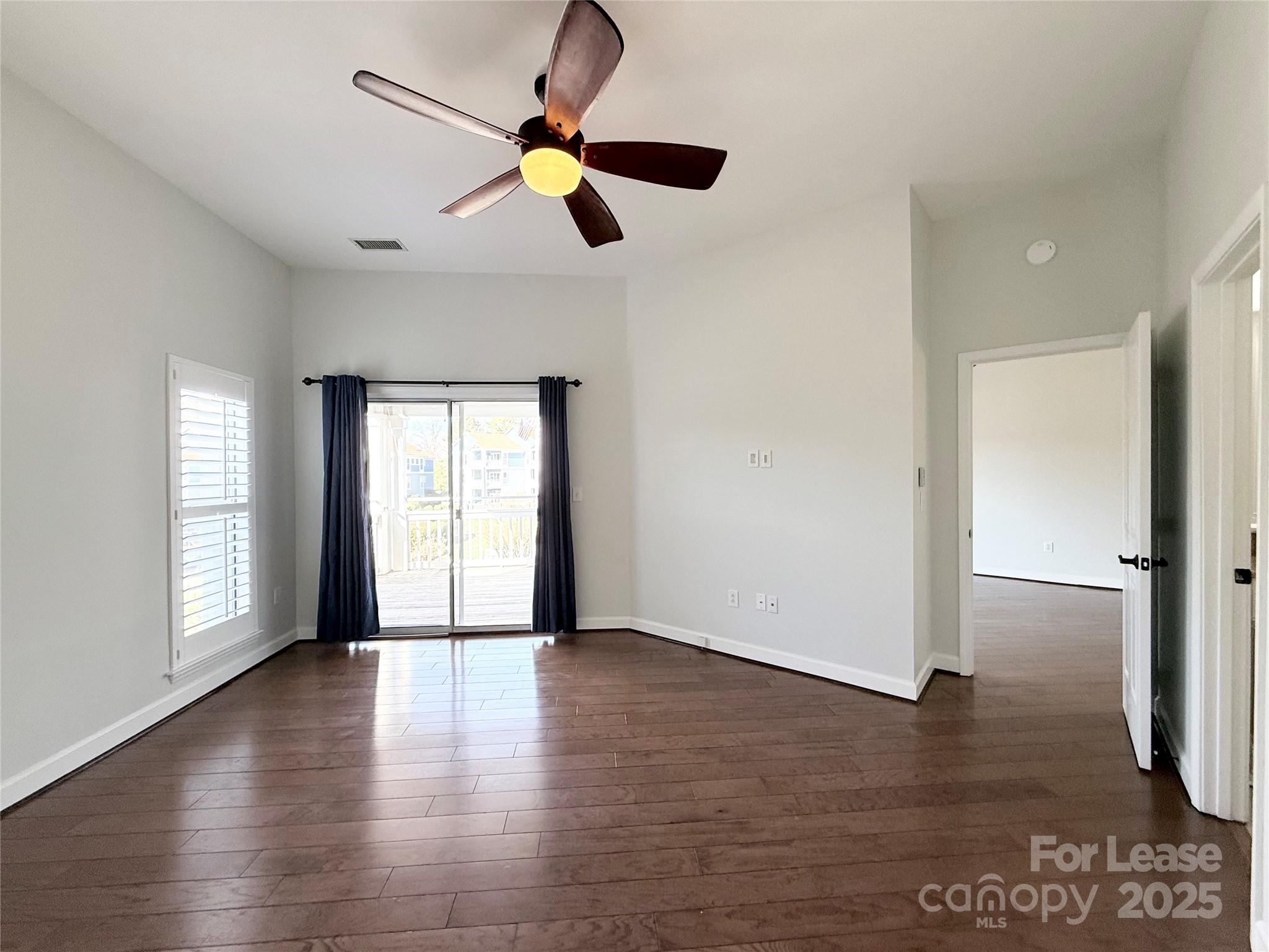 1133 Torrence Circle Davidson, NC 28036 - Photo 9 of 43 an empty room with wooden floor fan and windows