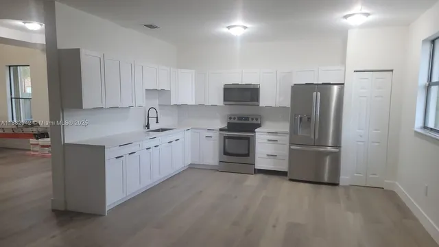 a kitchen with stainless steel appliances white cabinets and a refrigerator