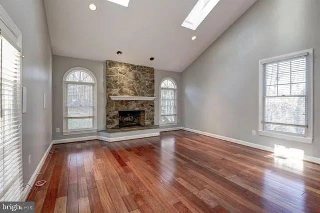 an empty room with wooden floor fireplace and windows