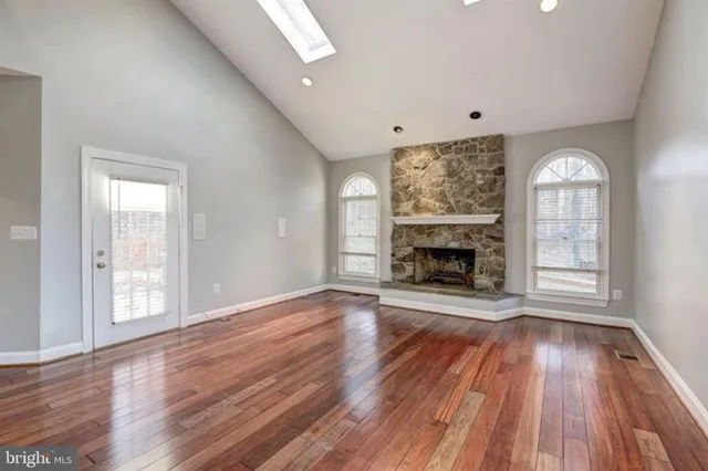a view of an empty room with wooden floor fireplace and a window