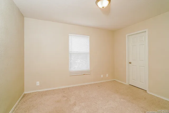 a view of an empty room with a window and a chandelier fan